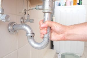 hand gripping pipe under sink
