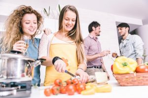 group of friends cooking at home to have dinner together. spending time with old friends and sharing good mood