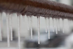Icicles hanging from a brown pipe. Frozen water and metal surface, winter time concept. selective focus shallow depth of field photo