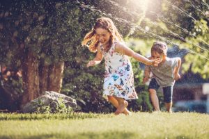 Happy kids playing with garden sprinkler 